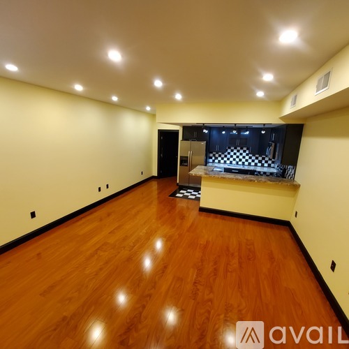 A spacious room with wooden flooring and a checkered patterned bar in the background.