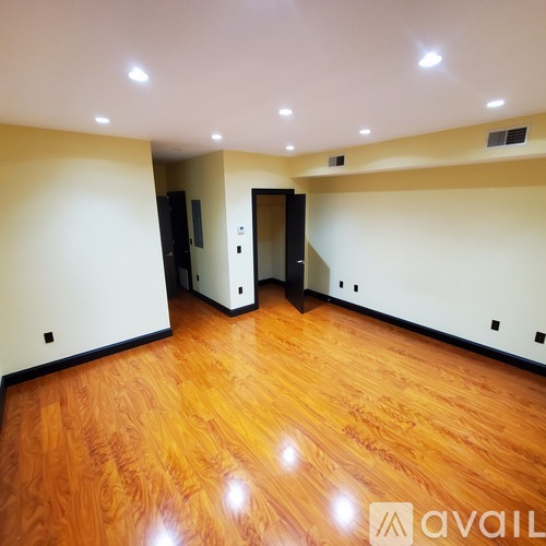 A room with wooden floors and a white wall with a door.