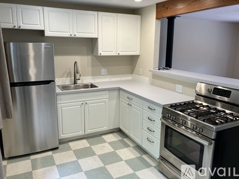 A kitchen with white cabinets and a checkered floor.