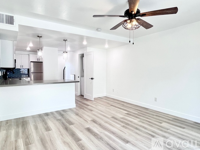 A spacious room with a ceiling fan and lighting fixtures.