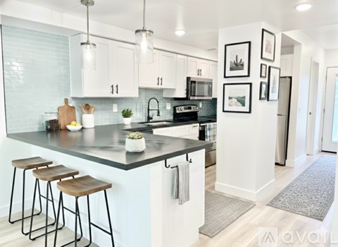 A kitchen with white cabinets and a black countertop.