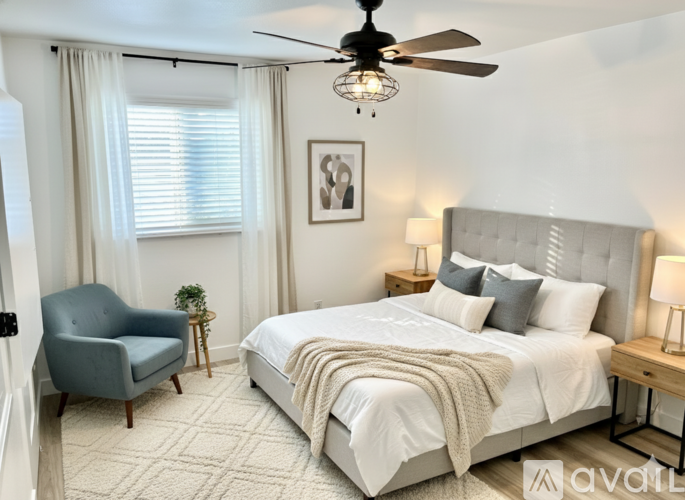 A bedroom with a large bed, a chair, and a ceiling fan.