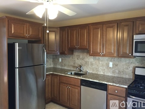 A kitchen with wooden cabinets and a stainless steel refrigerator.