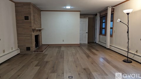 A room with wooden flooring and a fireplace.