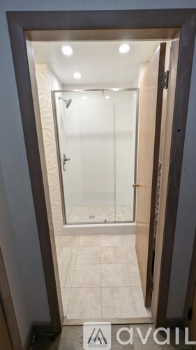 A bathroom with a glass shower door and tiled floor.