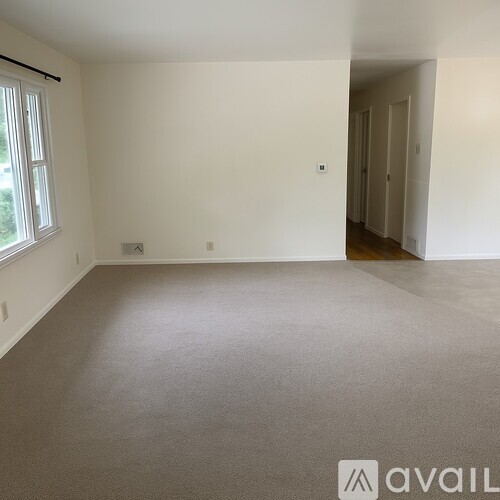 A spacious room with a carpeted floor and white walls.