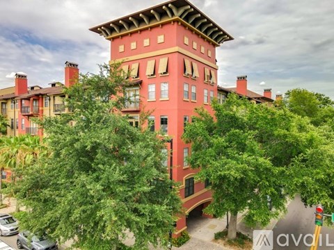 A red building with a tower and trees in front.