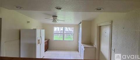 A kitchen with a refrigerator, a ceiling fan, and a window.