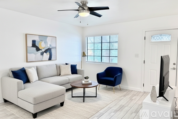 A living room with a grey couch, blue chair, and a painting on the wall.