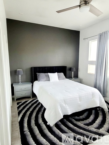 A bedroom with a large bed and a ceiling fan.