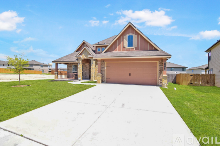 A house with a brown roof and a garage door is surrounded by a grassy area and other houses.