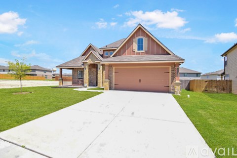 A house with a brown roof and a garage door is surrounded by a grassy area and other houses.