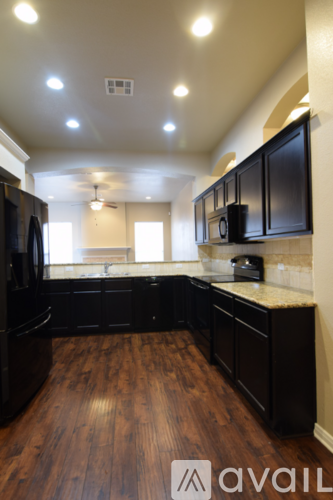A kitchen with black cabinets and a wooden floor.