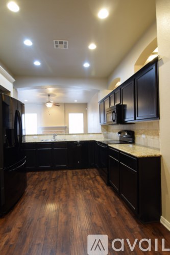 A kitchen with black cabinets and a wooden floor.