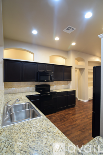 A kitchen with black cabinets and a stainless steel sink.