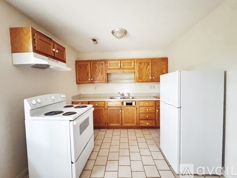 A kitchen with white appliances and wooden cabinets.