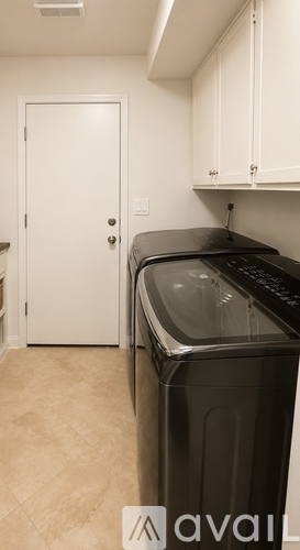 A black dishwasher is in a kitchen with white cabinets.