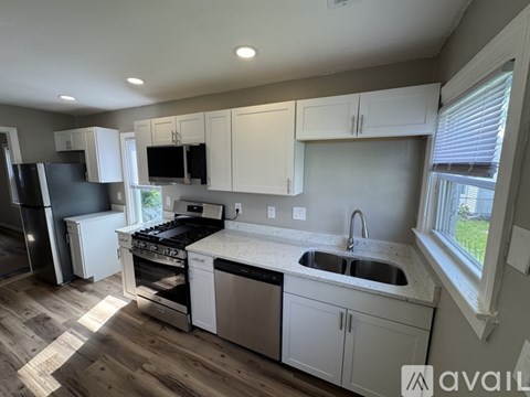 A kitchen with white cabinets and a black fridge.