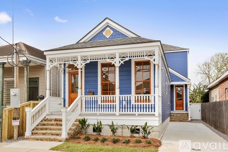 A blue house with a porch and a front yard.