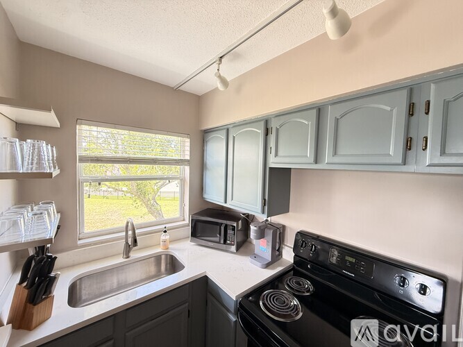 A kitchen with a black stove top oven and a window letting in natural light.