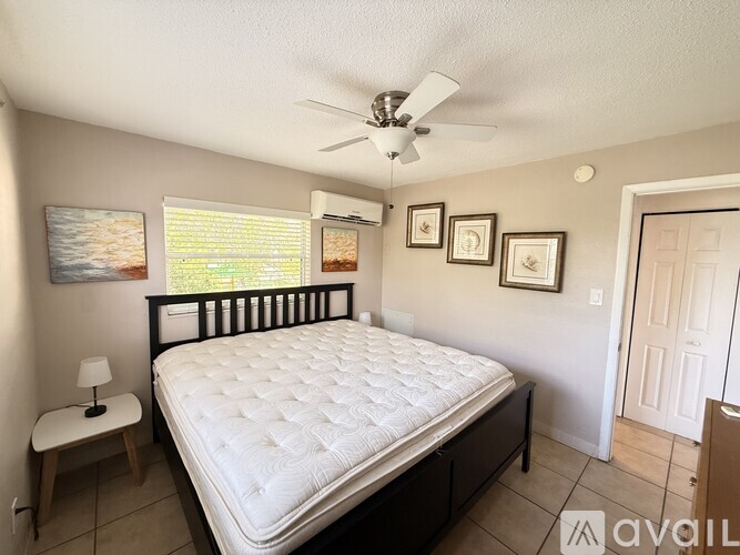 A bedroom with a bed, a fan, and pictures on the wall.