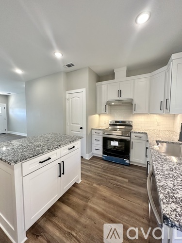 A kitchen with white cabinets and a granite countertop.