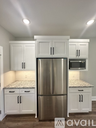 A kitchen with white cabinets and a stainless steel refrigerator.