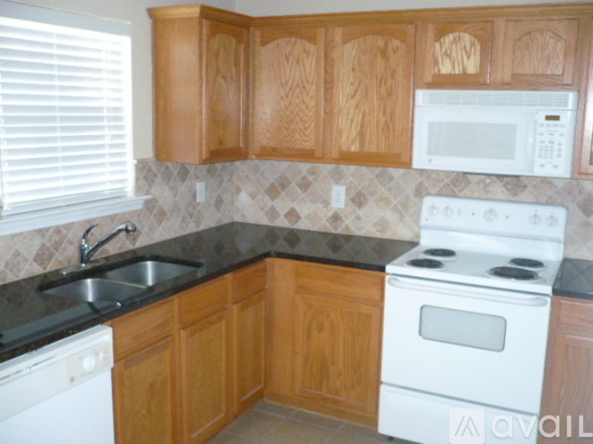 A kitchen with wooden cabinets and a white stove top oven.