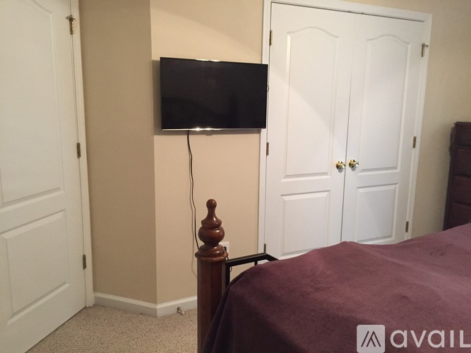 A bedroom with a bed, a television, and two doors.