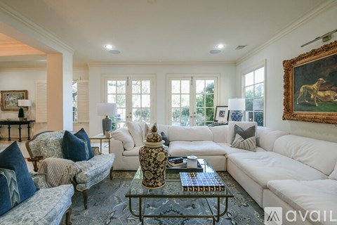 A living room with a white couch and a grey rug.