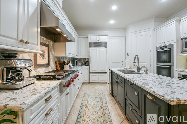A kitchen with white cabinets and a marble countertop.