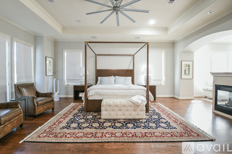 A bedroom with a four poster bed and a rug on the floor.