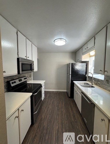 A kitchen with white cabinets and a black fridge.