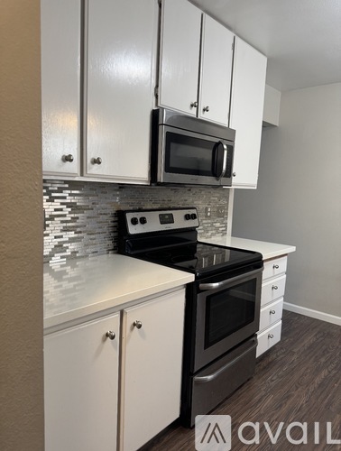 A kitchen with white cabinets and a black stove top oven.