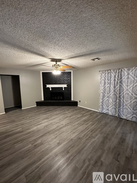 A room with wooden flooring and a fireplace.