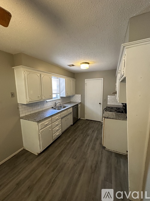 A kitchen with white cabinets and a wooden floor.
