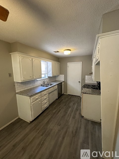 A kitchen with white cabinets and a wooden floor.
