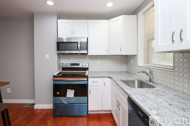 A kitchen with white cabinets and a marble countertop.