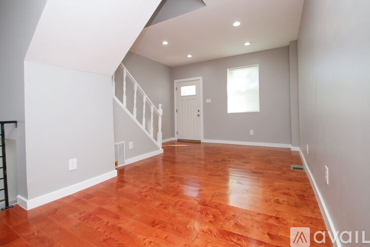A room with wooden floors and a staircase leading to another room.