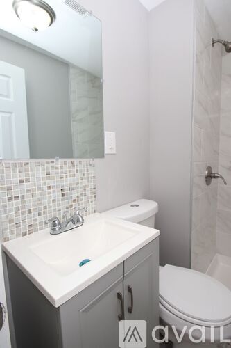 A bathroom with a white sink and grey cabinet.