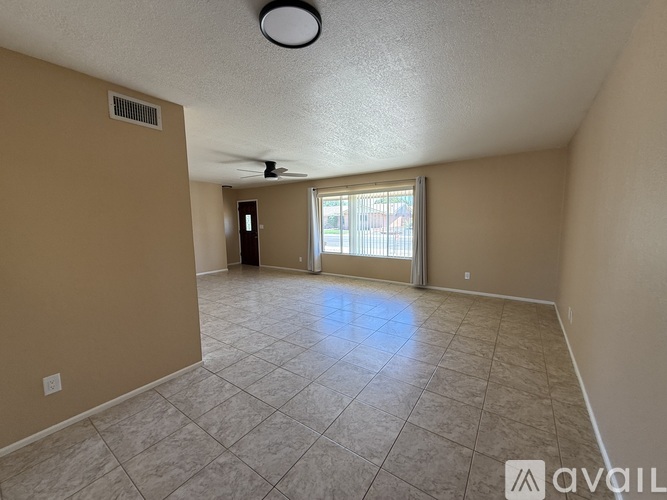 A spacious room with beige walls and a tiled floor.