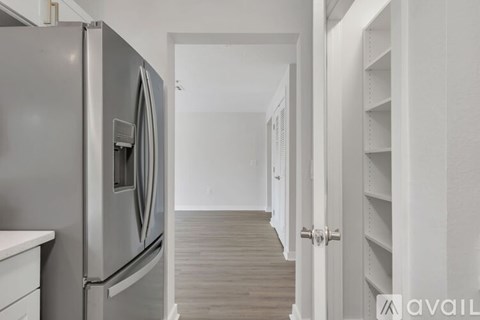 A kitchen with a stainless steel refrigerator and white cabinets.
