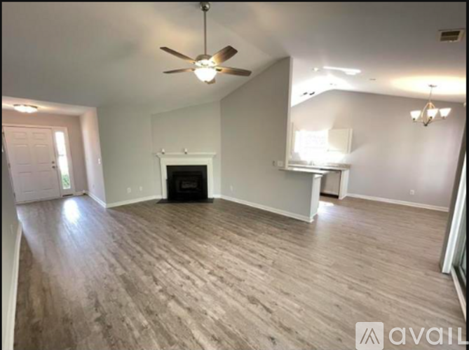 A spacious room with a fireplace and a ceiling fan.
