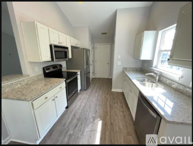 A kitchen with white cabinets and granite countertops.