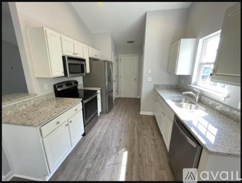 A kitchen with white cabinets and granite countertops.