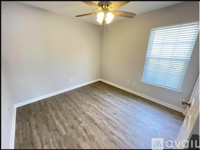 A room with a ceiling fan and a window with blinds.