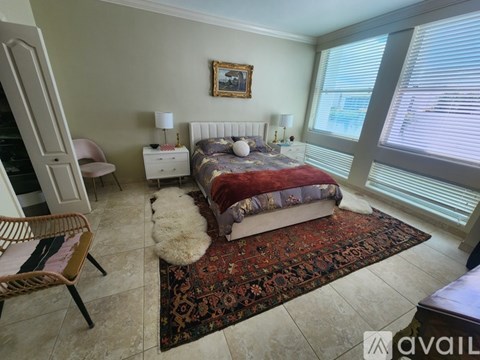 A bedroom with a large bed and a chair.