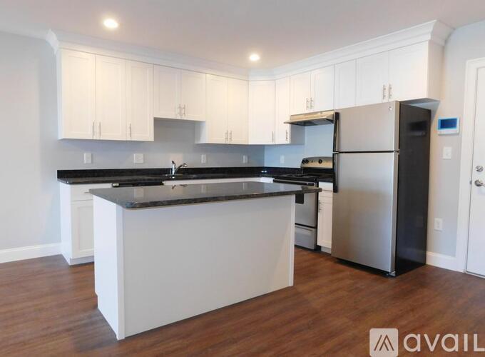 A kitchen with white cabinets and a black countertop.