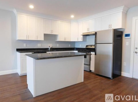A kitchen with white cabinets and a black countertop.