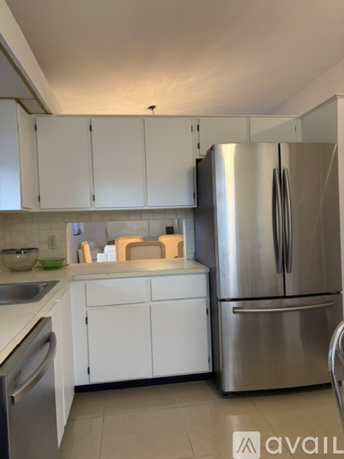 A kitchen with white cabinets and a stainless steel refrigerator.